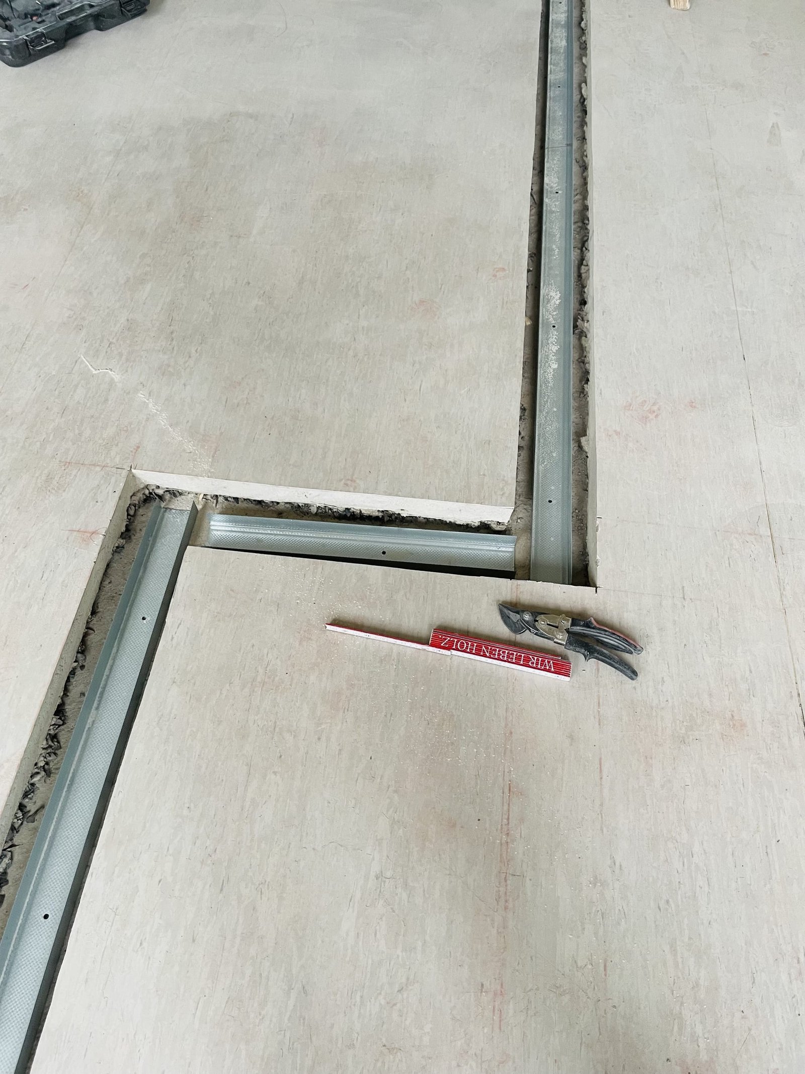 In Bodenaussparungen sind Metallprofile in L‑Form eingelegt.